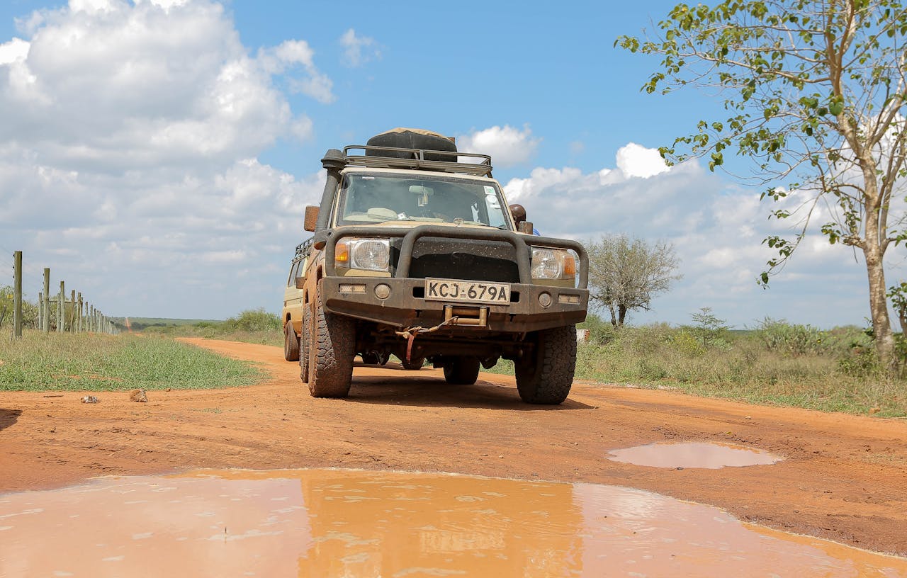 Home A rugged 4x4 SUV navigating a muddy outdoor trail under a bright sky.